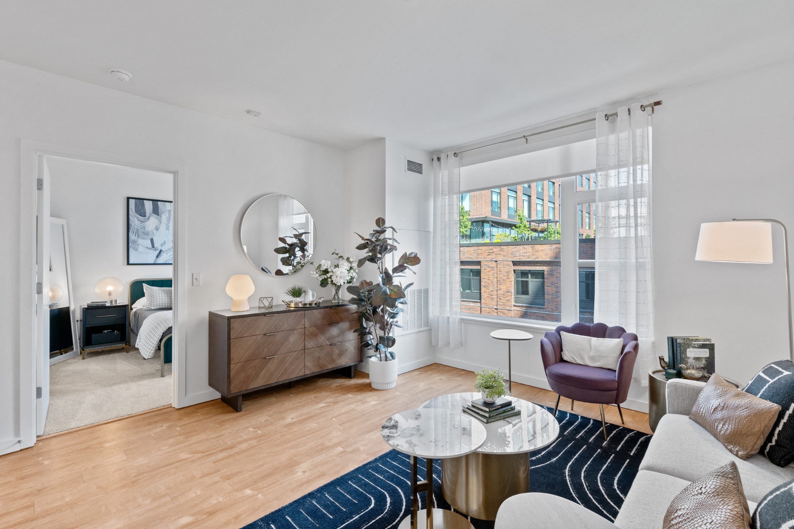 a living room with a large window and a blue rug